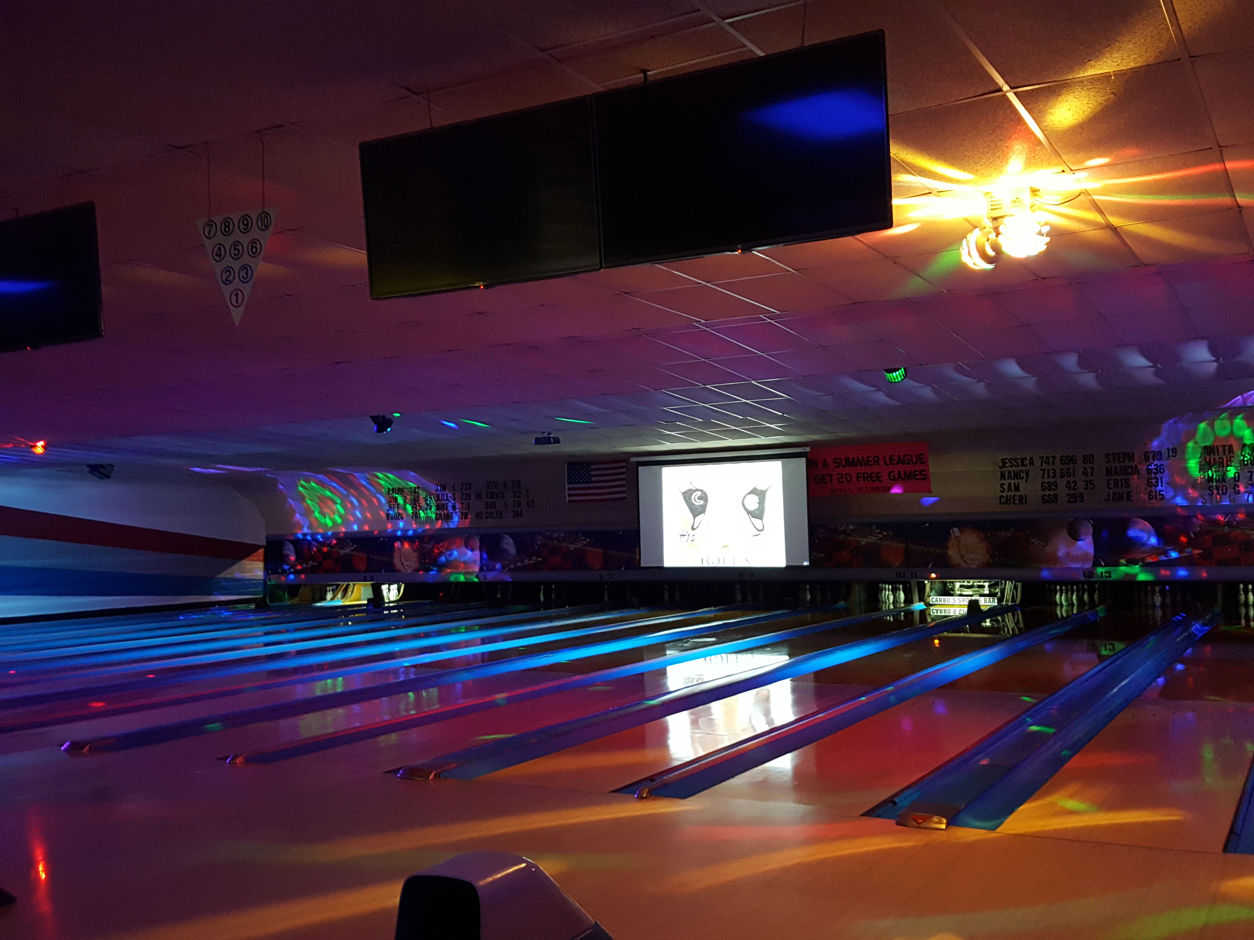 Glow-in-the-dark bowling lanes with vibrant neon blue lighting and colorful patterns projected on the ceiling.