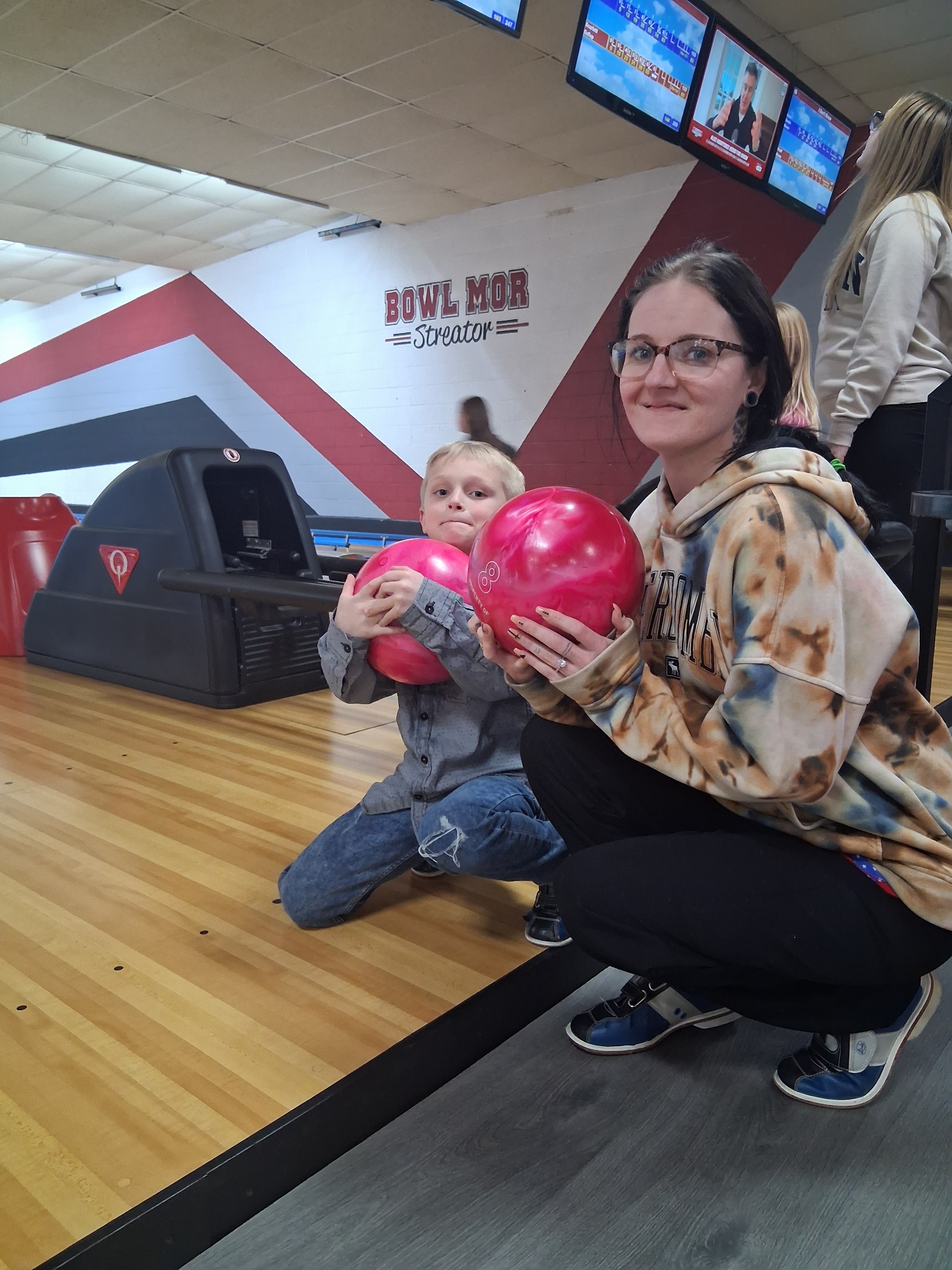 A woman and a young boy pose with red bowling balls on the lanes at Bowl Mor Streator.