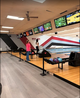 Two people standing on a bowling approach at Bowl Mor Streator featuring modern scoring monitors and ball returns.