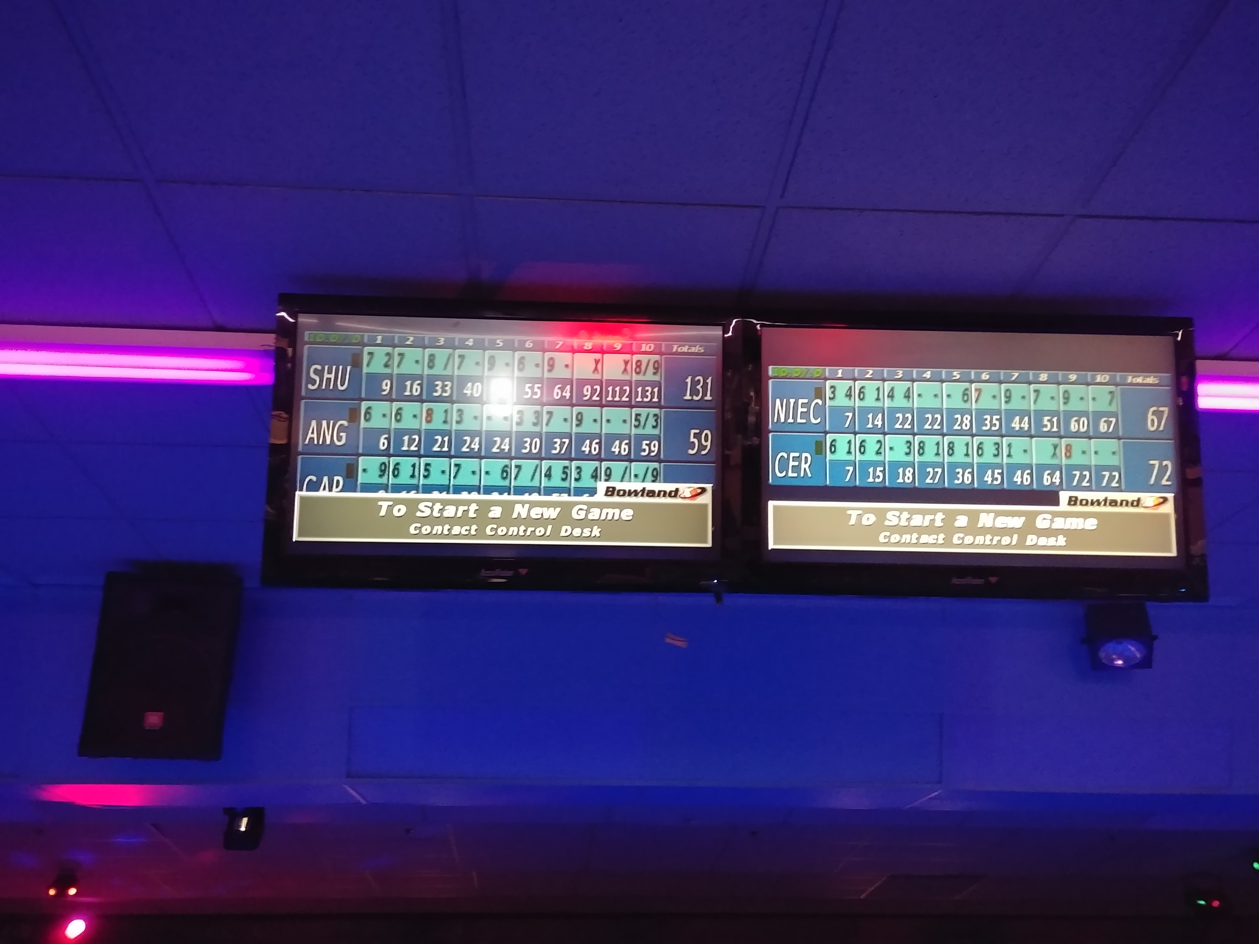 Two digital bowling score monitors showing player names and frame scores under blue and pink cosmic lighting.