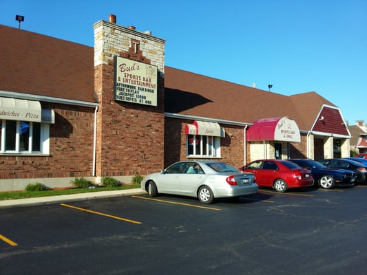 The brick exterior of Bud's Sports Bar and Entertainment with a parking lot and clear blue sky.