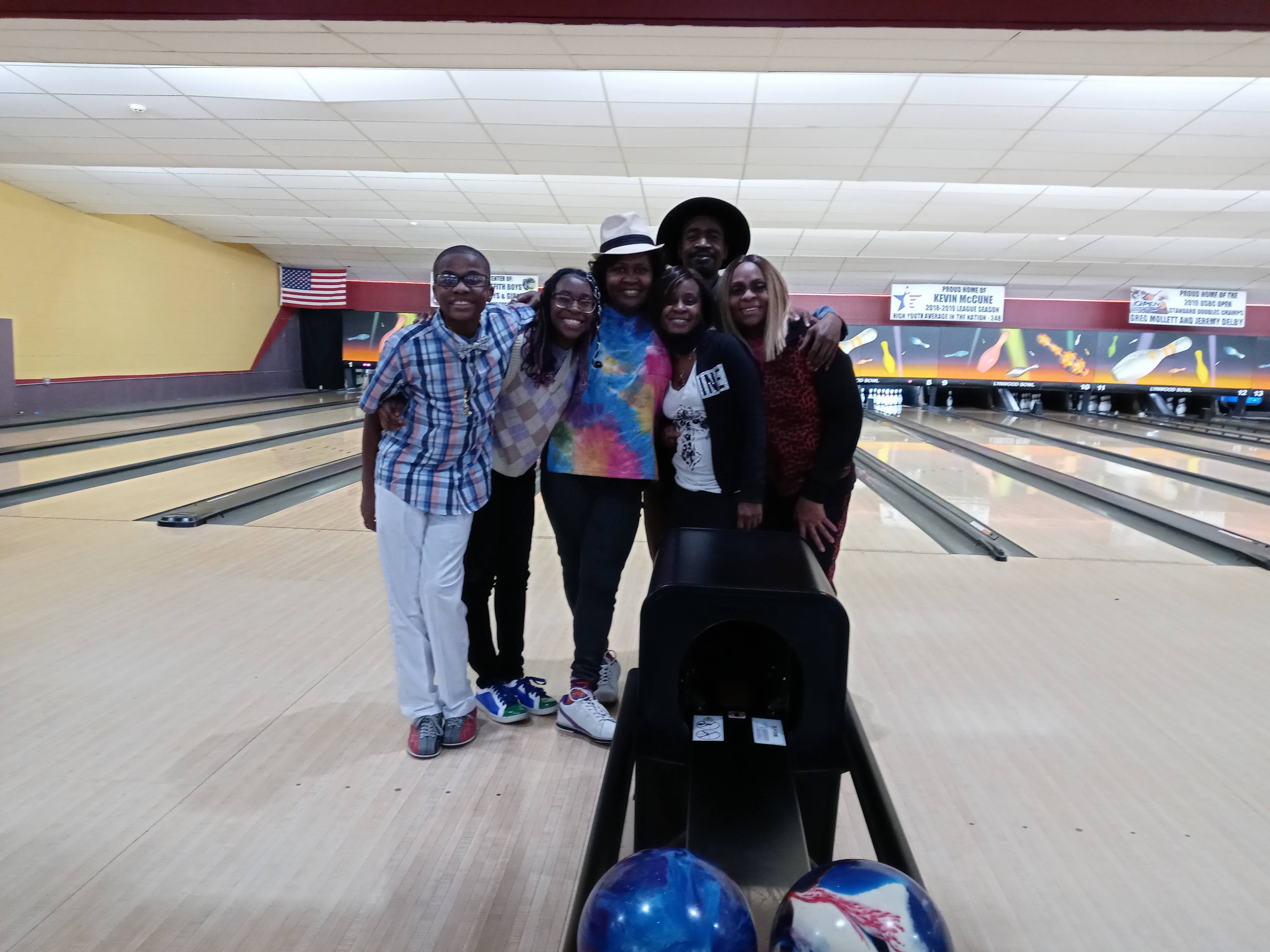 A group of six people posing together for a photo on a bowling lane at Lynwood Bowl.