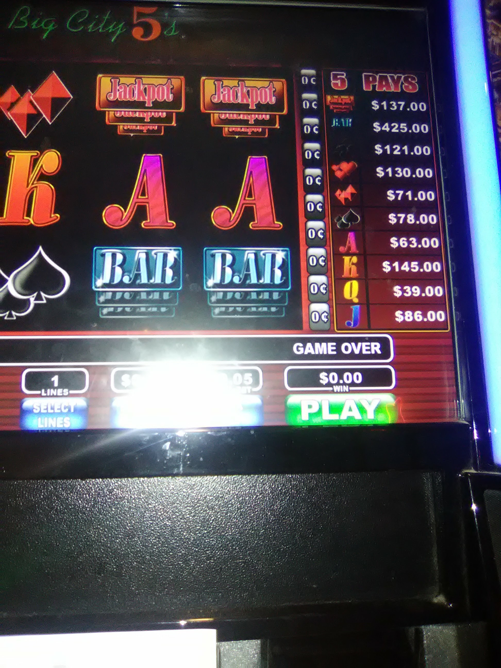 Close-up of a video gaming terminal screen displaying a slot machine game with a bright light reflection.