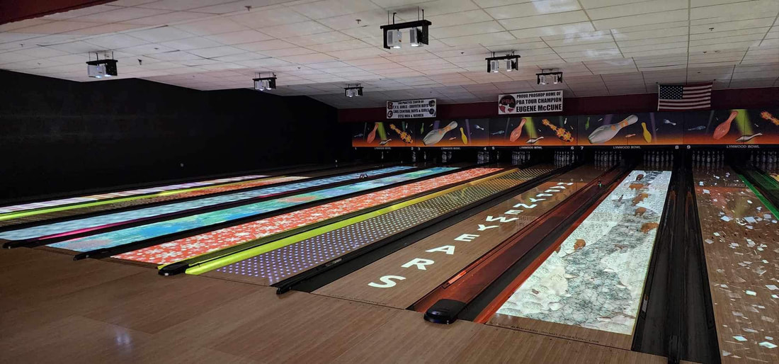 Bowling lanes displayi ng colorful projecte d patterns like snowflak es and a river in a dimly lit alley.