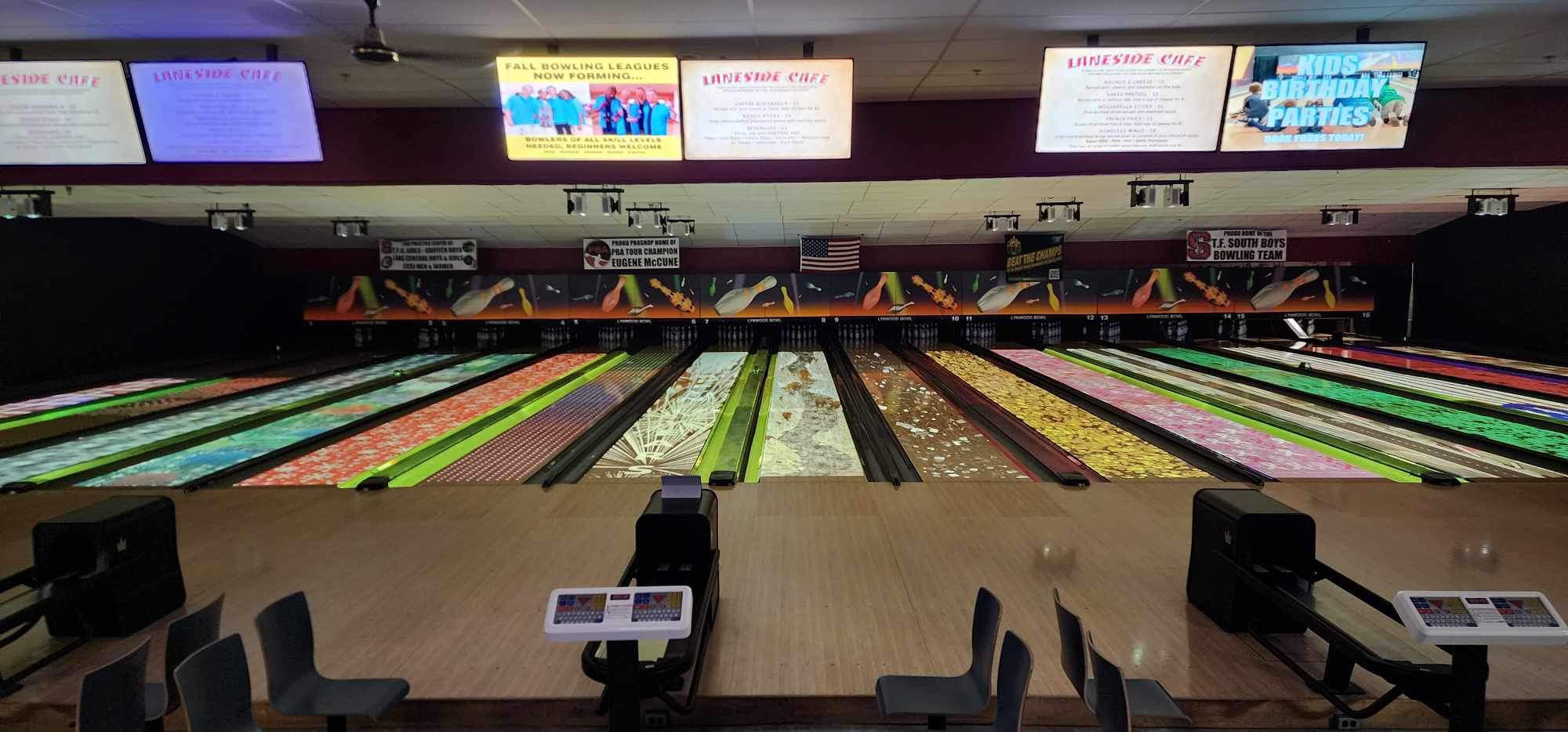 Wide view of bowling lanes at Lynwood Bowl featuring custom graphic lane skins and overhead digital monitors.