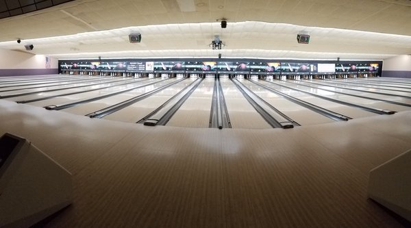 A wide-angle view of numerous polished bowling lanes inside Liberty Lanes.