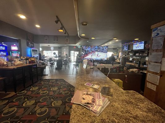 A bowling alley sports bar and lounge area with televisions showing basketball and high-top seating.