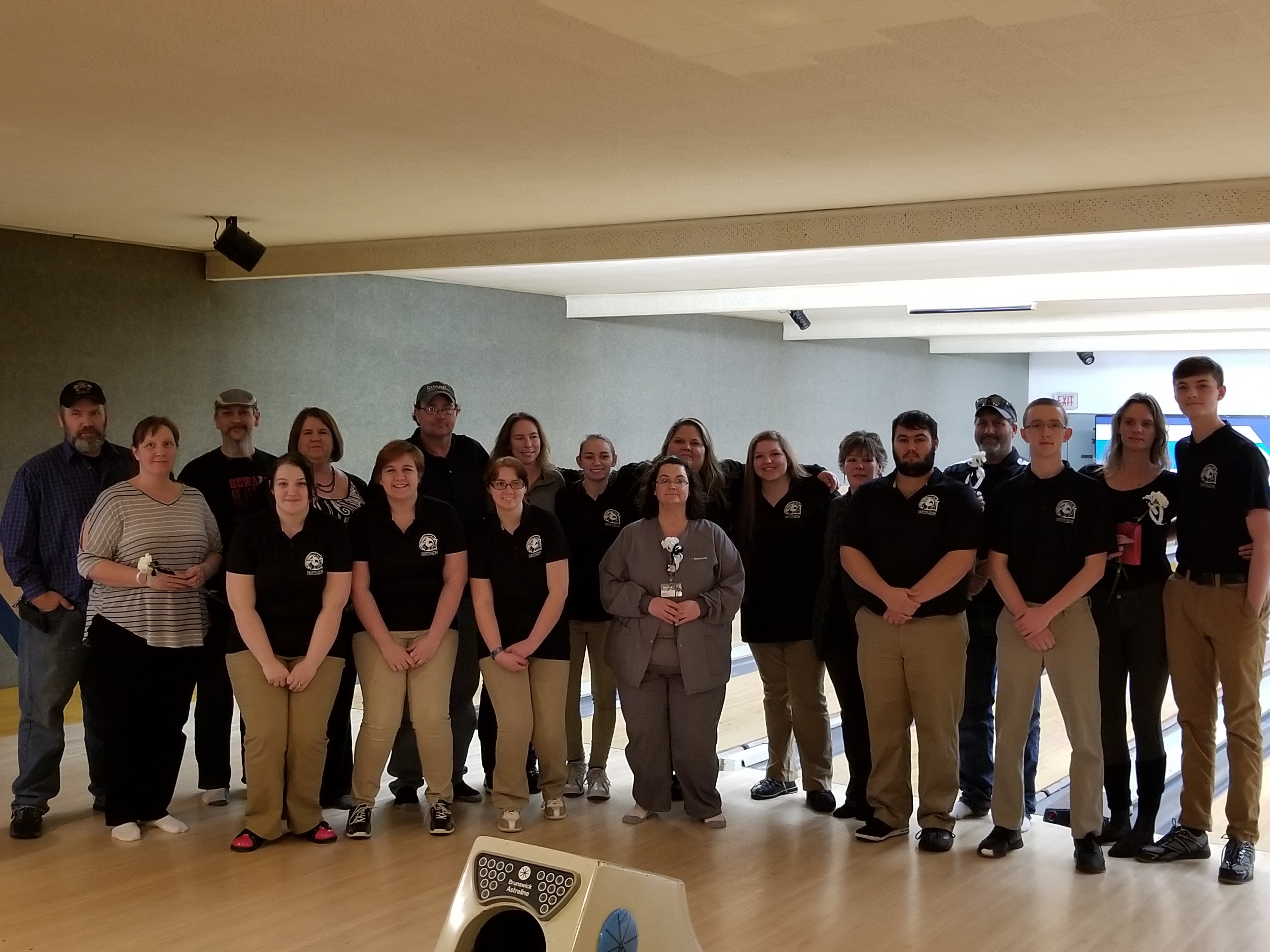 A large group of people posing for a group portrait on the bowling lanes.