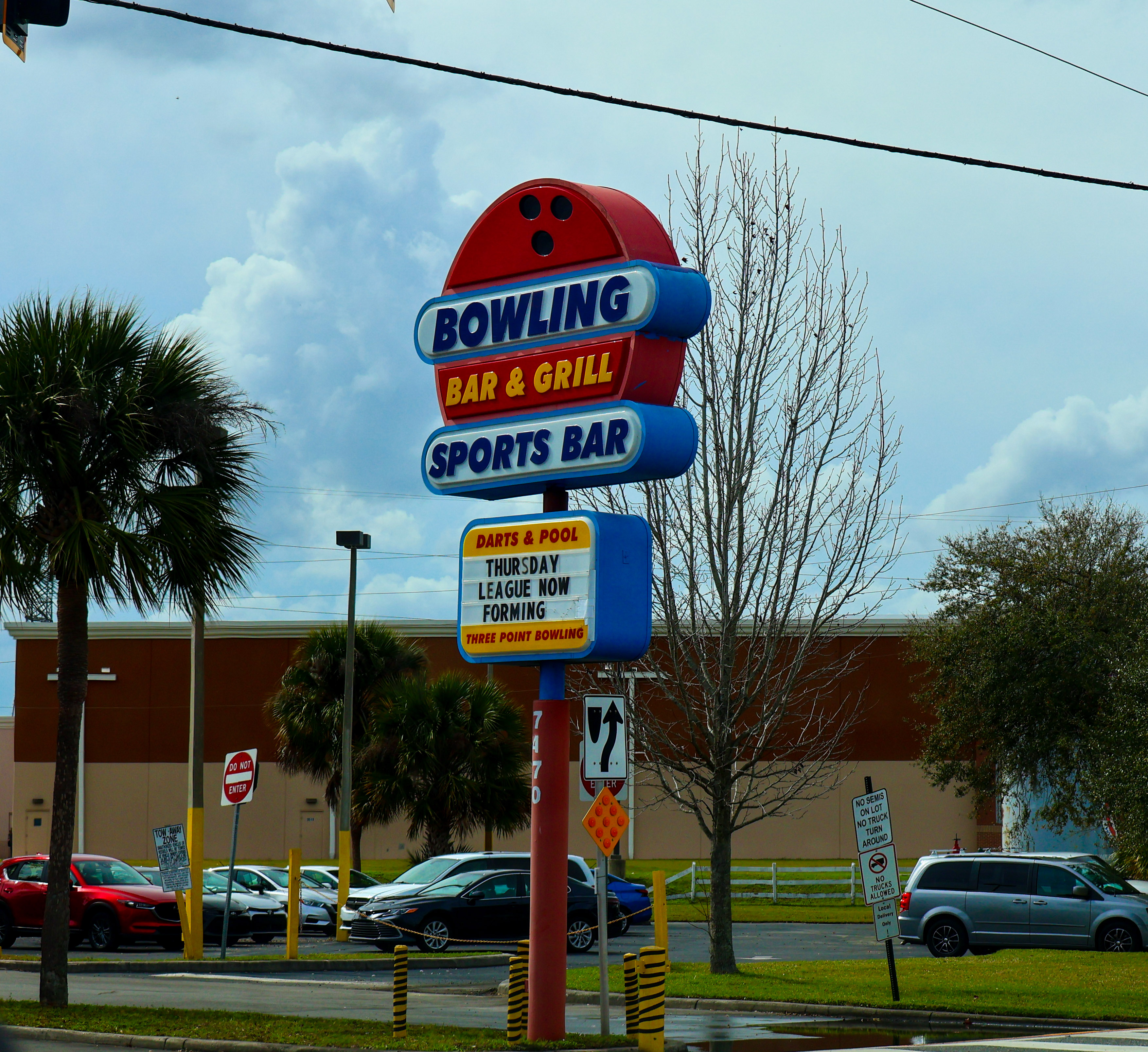 Street sign for Three Point Bowling showing the bar, grill, sports bar, and league announcements.