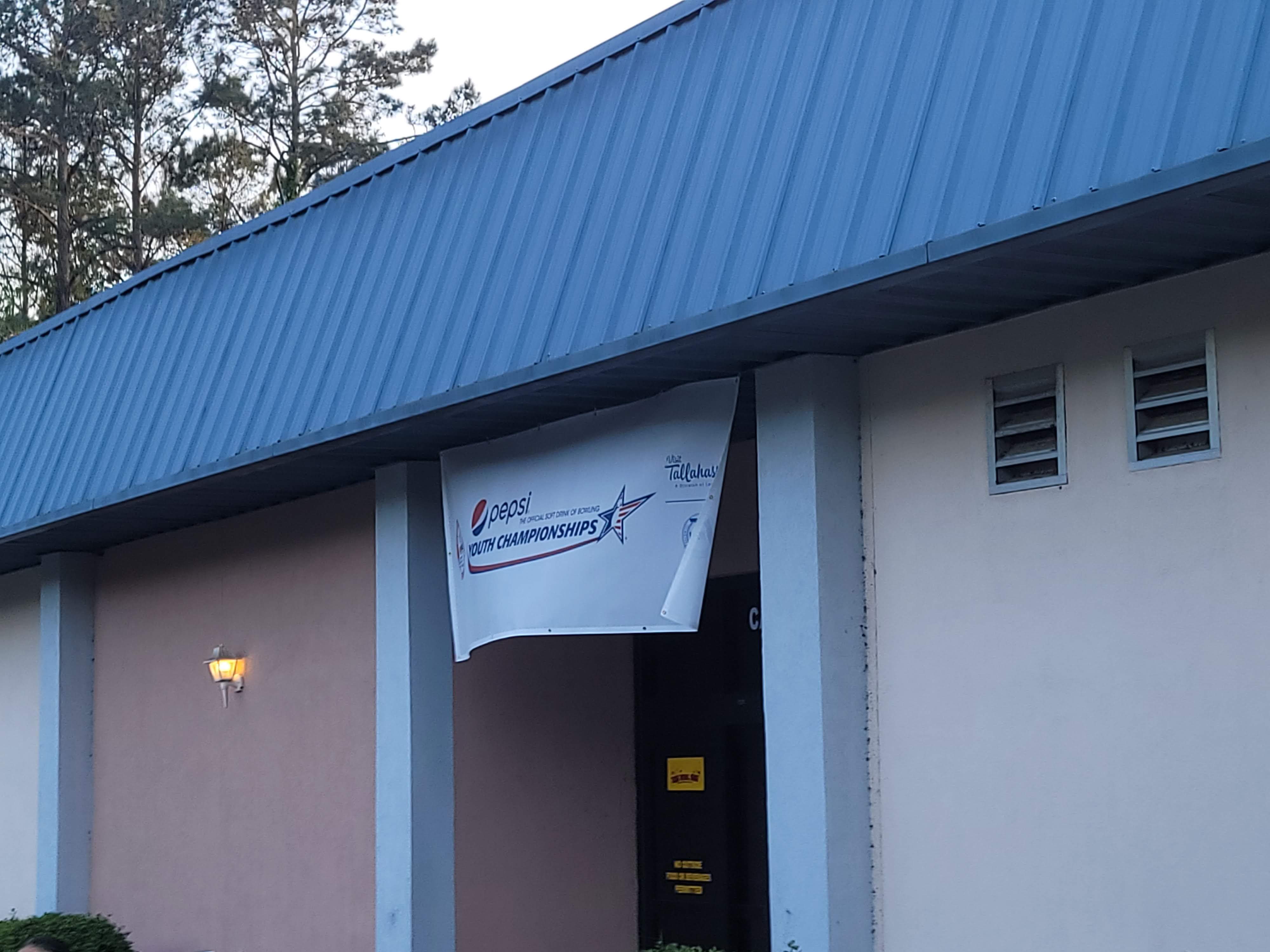 An exterior view of the building showing a blue metal roof and a Pepsi Youth Championships banner.