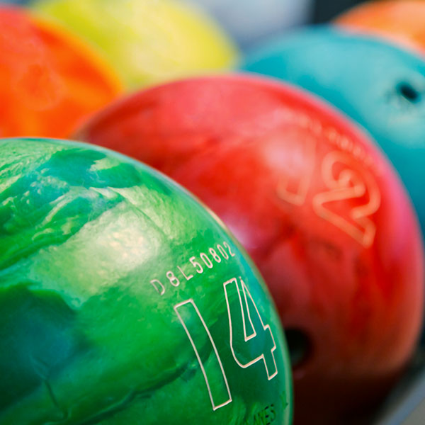 Close-up of a green bowling ball numbered 14 in front of other colorful bowling balls.