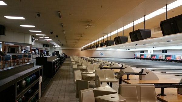 Wide view of bowling lanes, seating, and overhead monitors inside Little River Lanes.