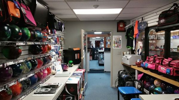 An interior view of a professional bowling shop with rows of bowling balls and equipment on display shelves.