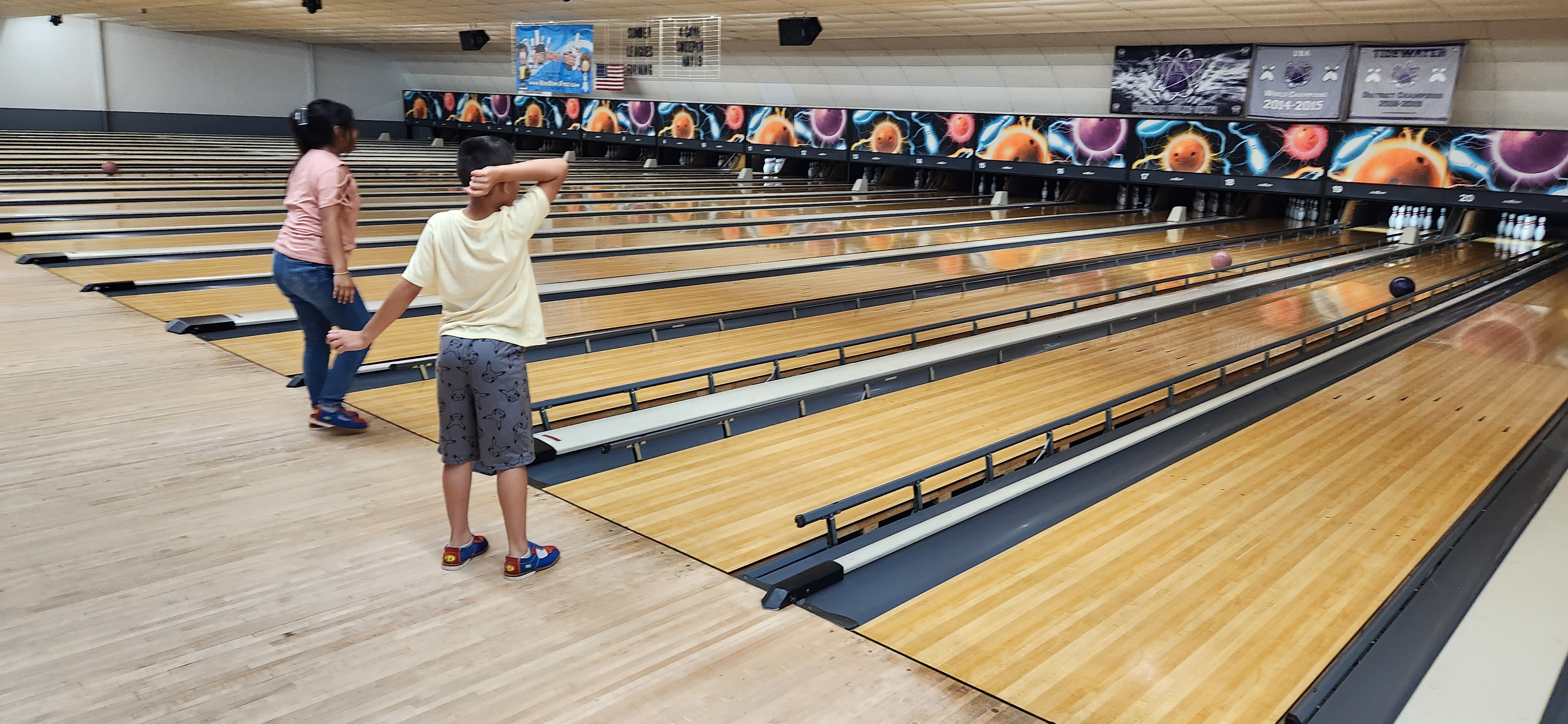 Two children bowl on wood lanes with bumper rails at Lumberton Bowling Center.