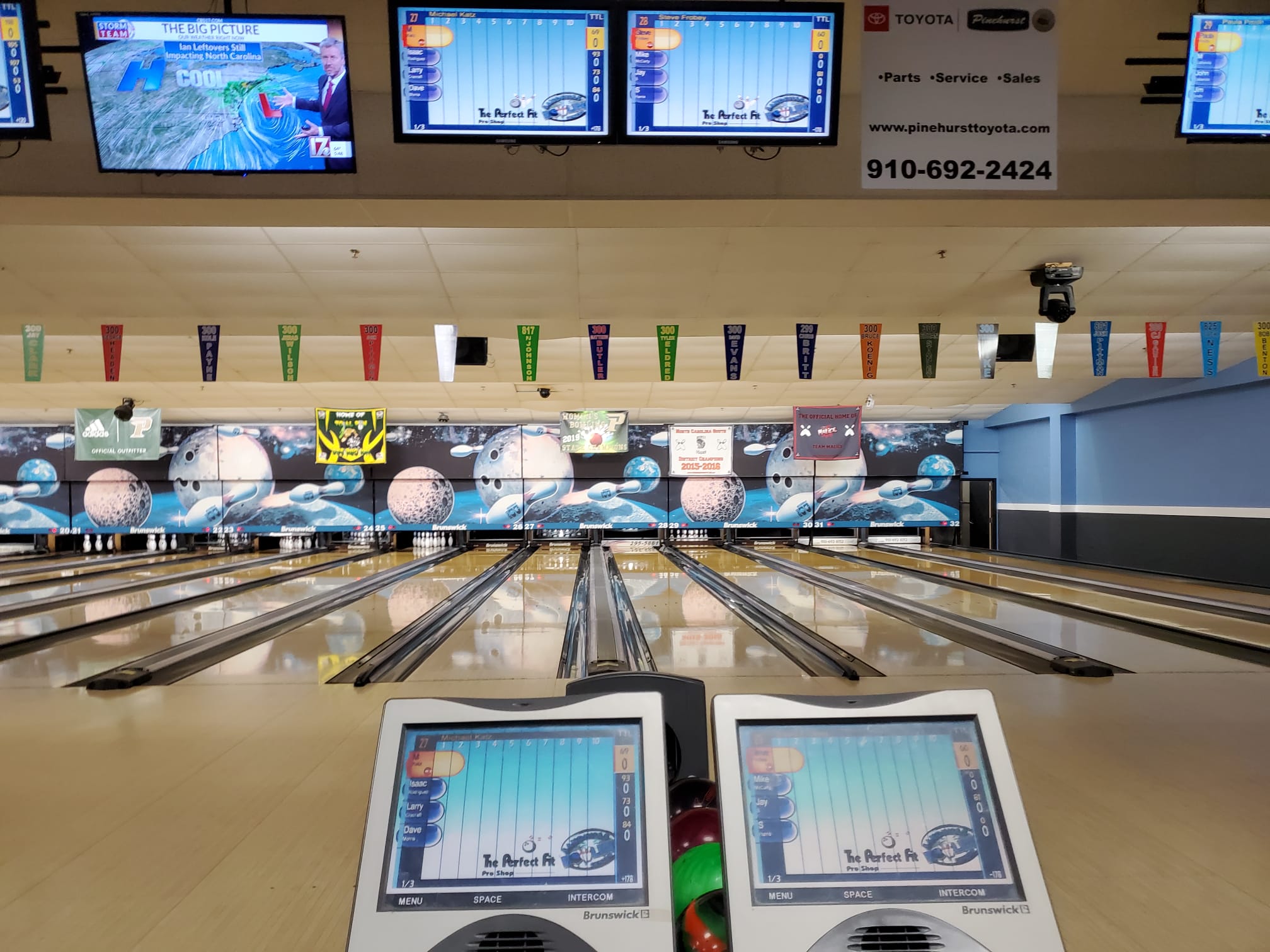 A clean view of multiple bowling lanes with modern electronic scoring tablets in the foreground.