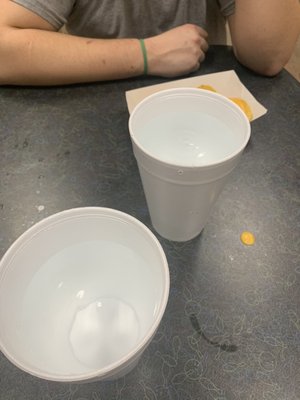 Two white cups and a small plate of food sit on a table with a bowling pin pattern.