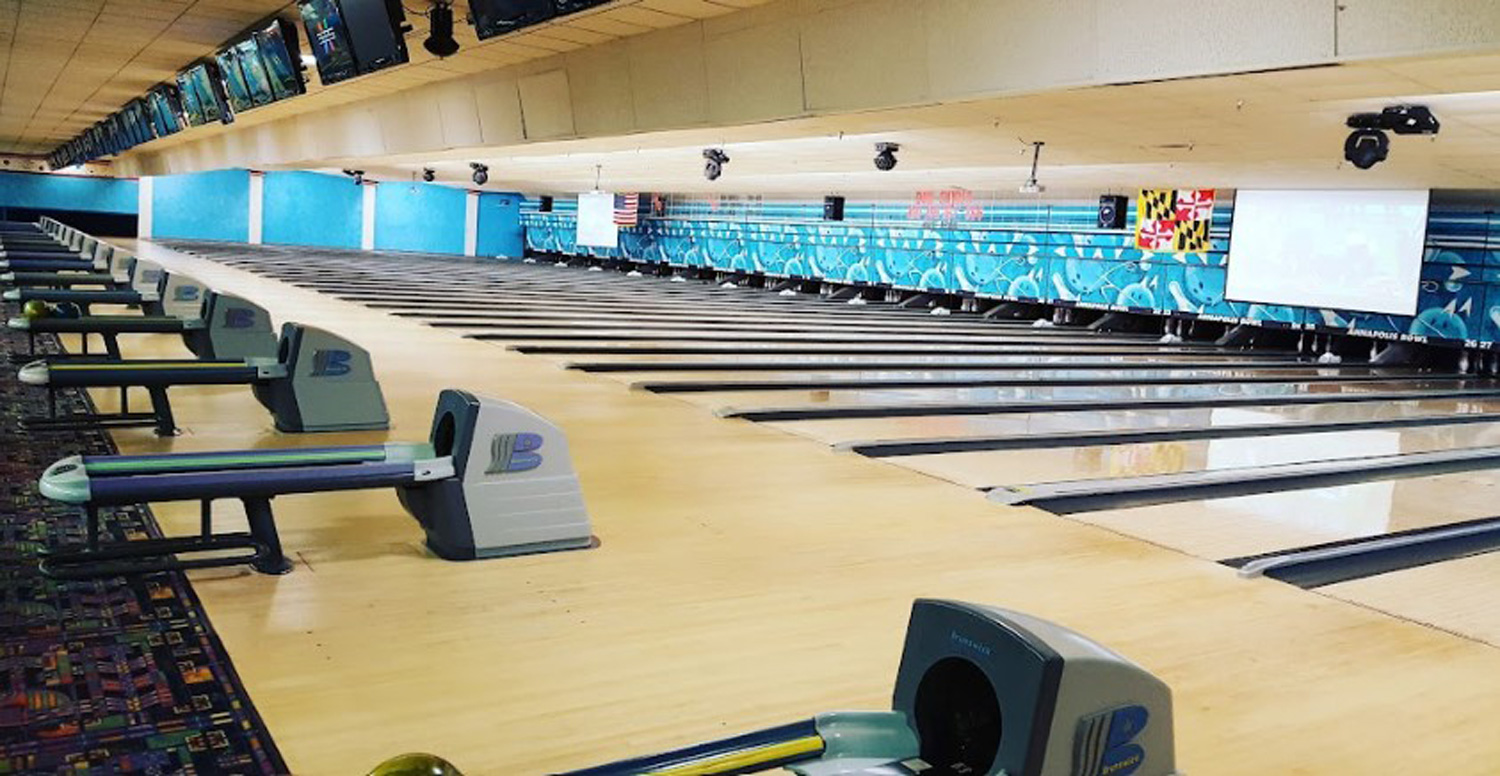 A wide view of numerous polished bowling lanes and ball returns at Annapolis Bowl.
