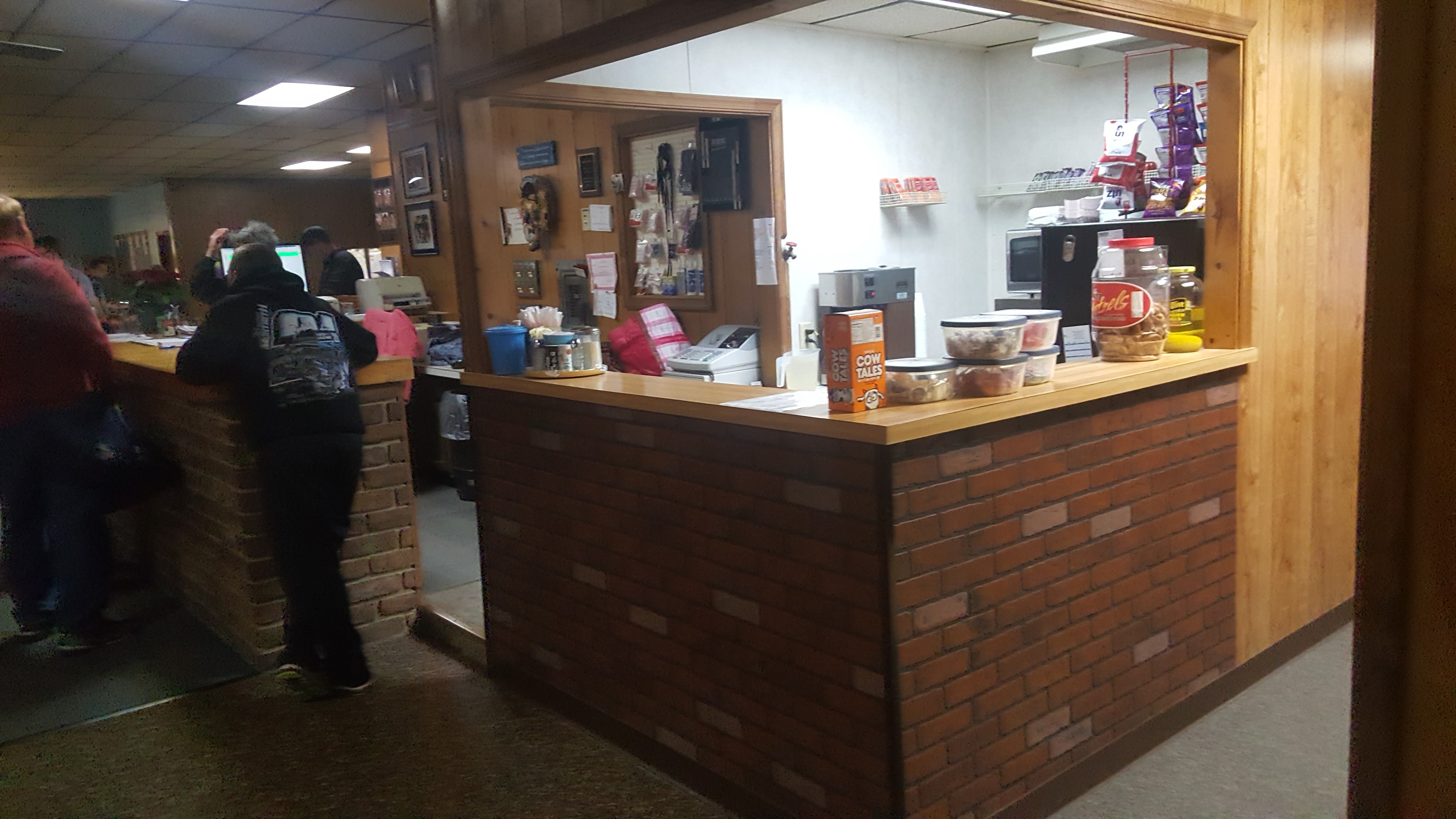 Interior view of a bowling center snack bar with brick counters, wood paneling, and various snacks on display.