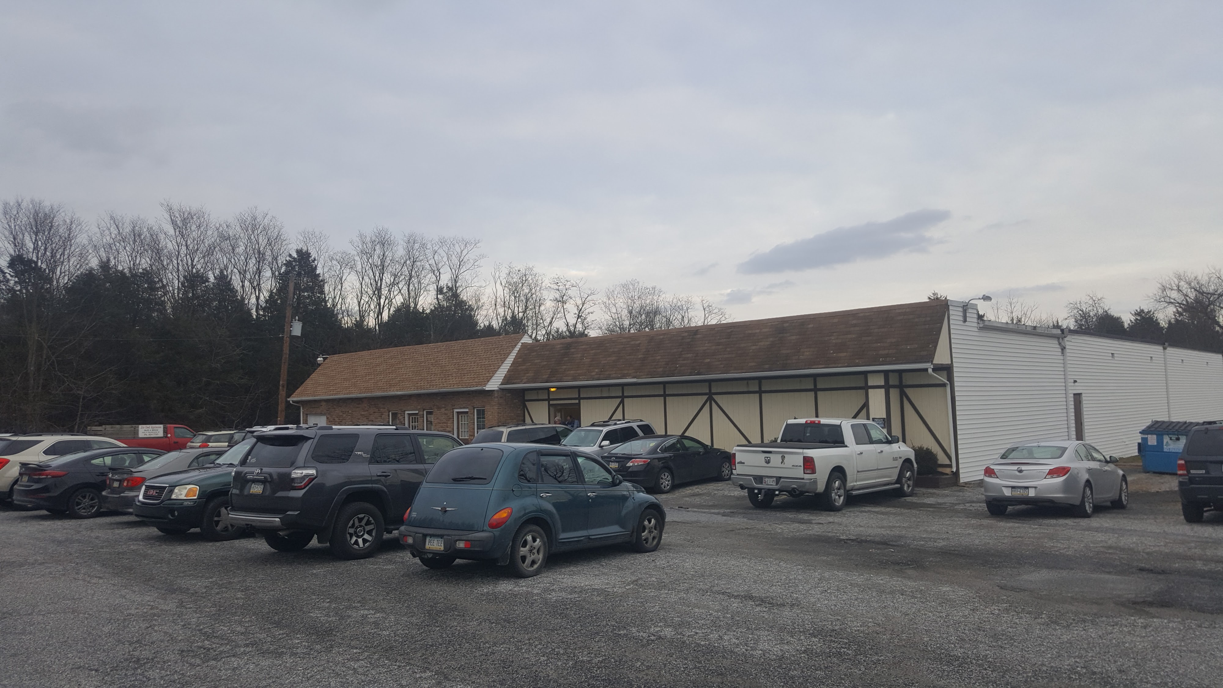 The exterior of Edgewood Bowl showing the building and a large gravel parking lot with several cars.