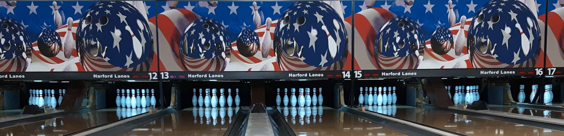 A wide panoramic view of several bowling lanes at Harford Lanes featuring patriotic-themed masking units.