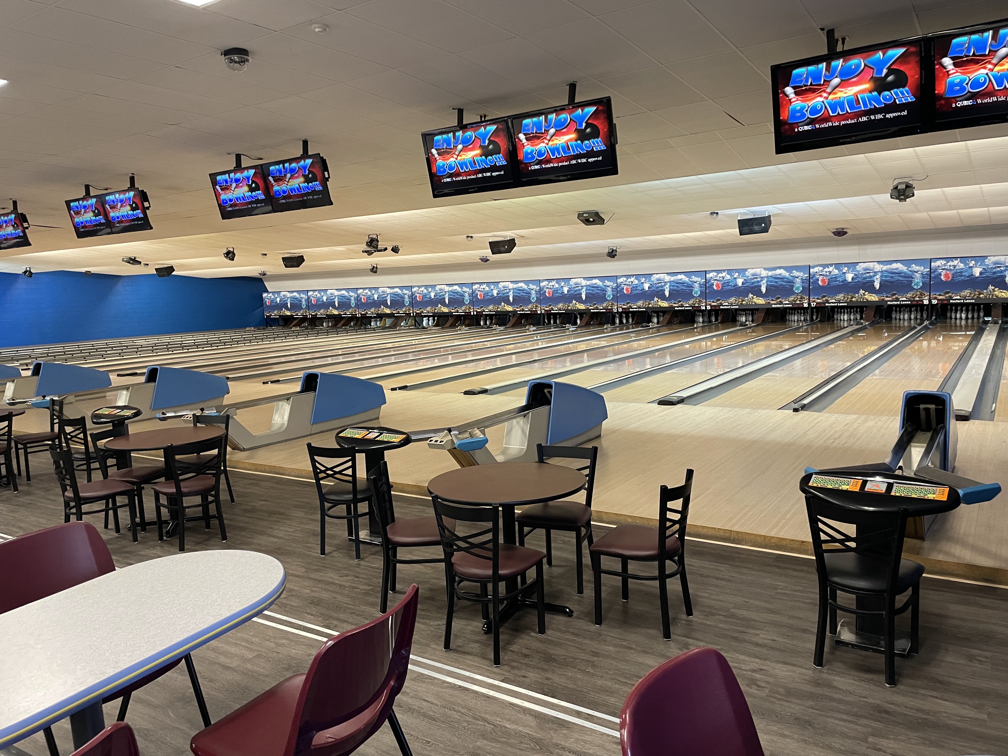 Interior view of Harford Lanes showing multiple bowling lanes, overhead monitors, and seating area.