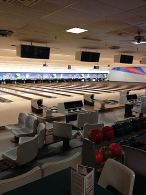 An interior view of a bowling alley showing the lanes, ball racks, and automatic scoring consoles.