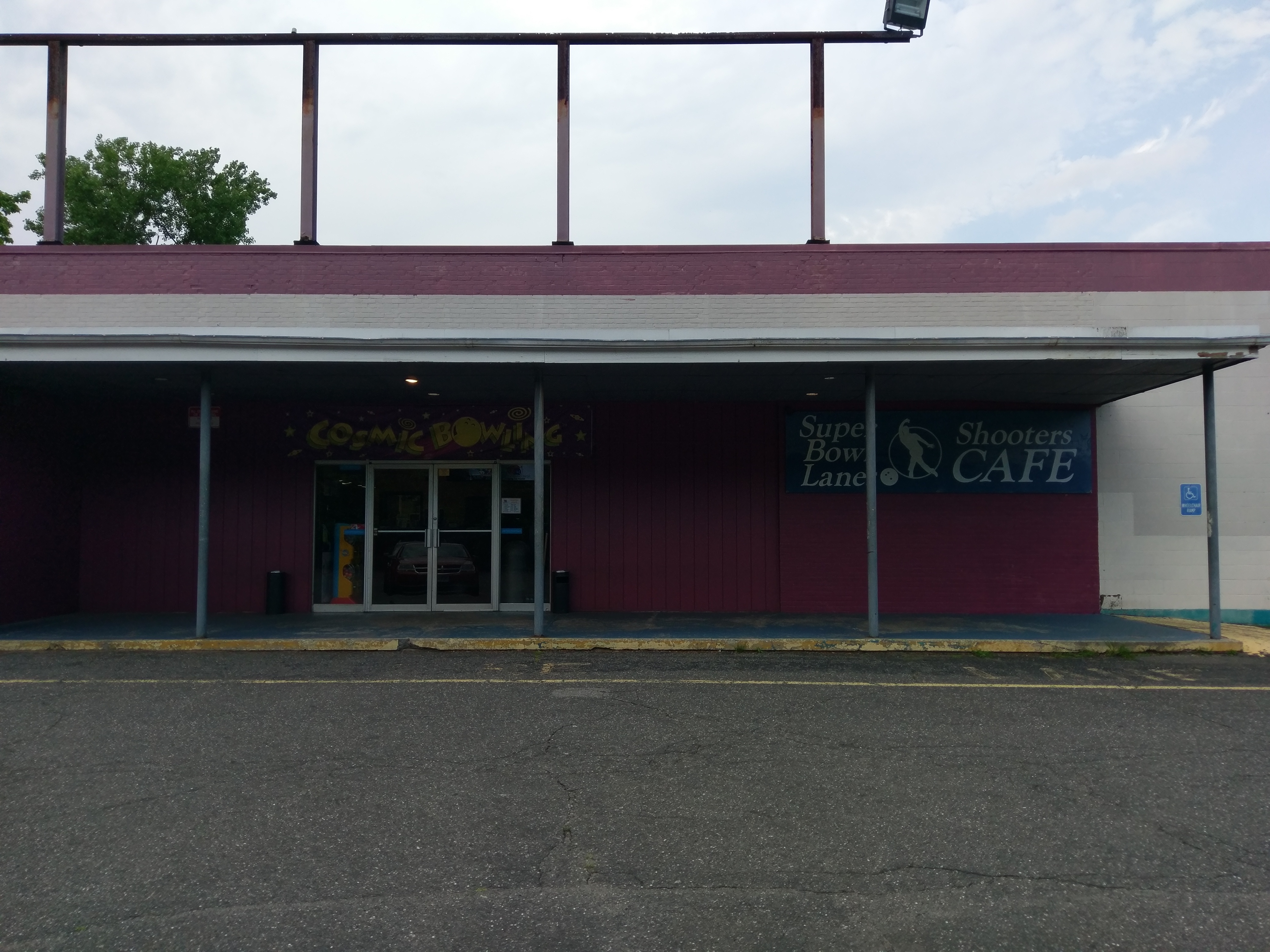 The exterior entrance of a bowling center featuring signs for cosmic bowling and a cafe.