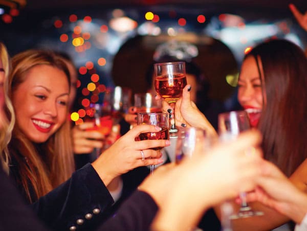 A group of friends smiling and raising their glasses together in a celebratory toast.
