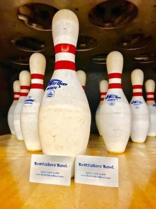 Brattleboro Bowl business cards sitting in front of a rack of bowling pins on a lane.