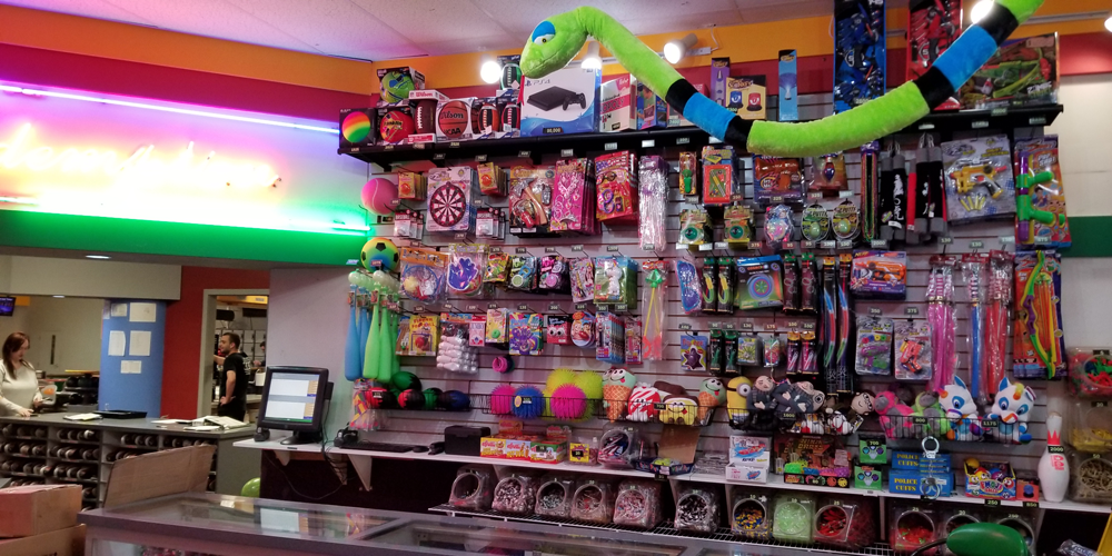 An arcade redemption counter stocked with various toys, games, and candy prizes.