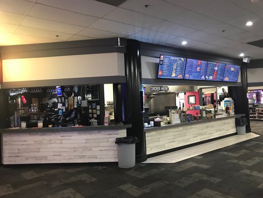 A modern bowling center snack bar and beverage counter with digital menu boards and a white wood-plank finish.