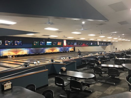 A wide interior view of a bowling center with multiple lanes, digital scoreboards, and rows of seating.