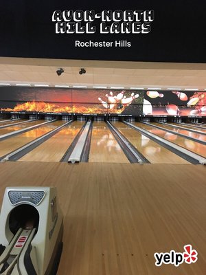A vertical view of polished bowling lanes with fiery graphics and the center name overhead.