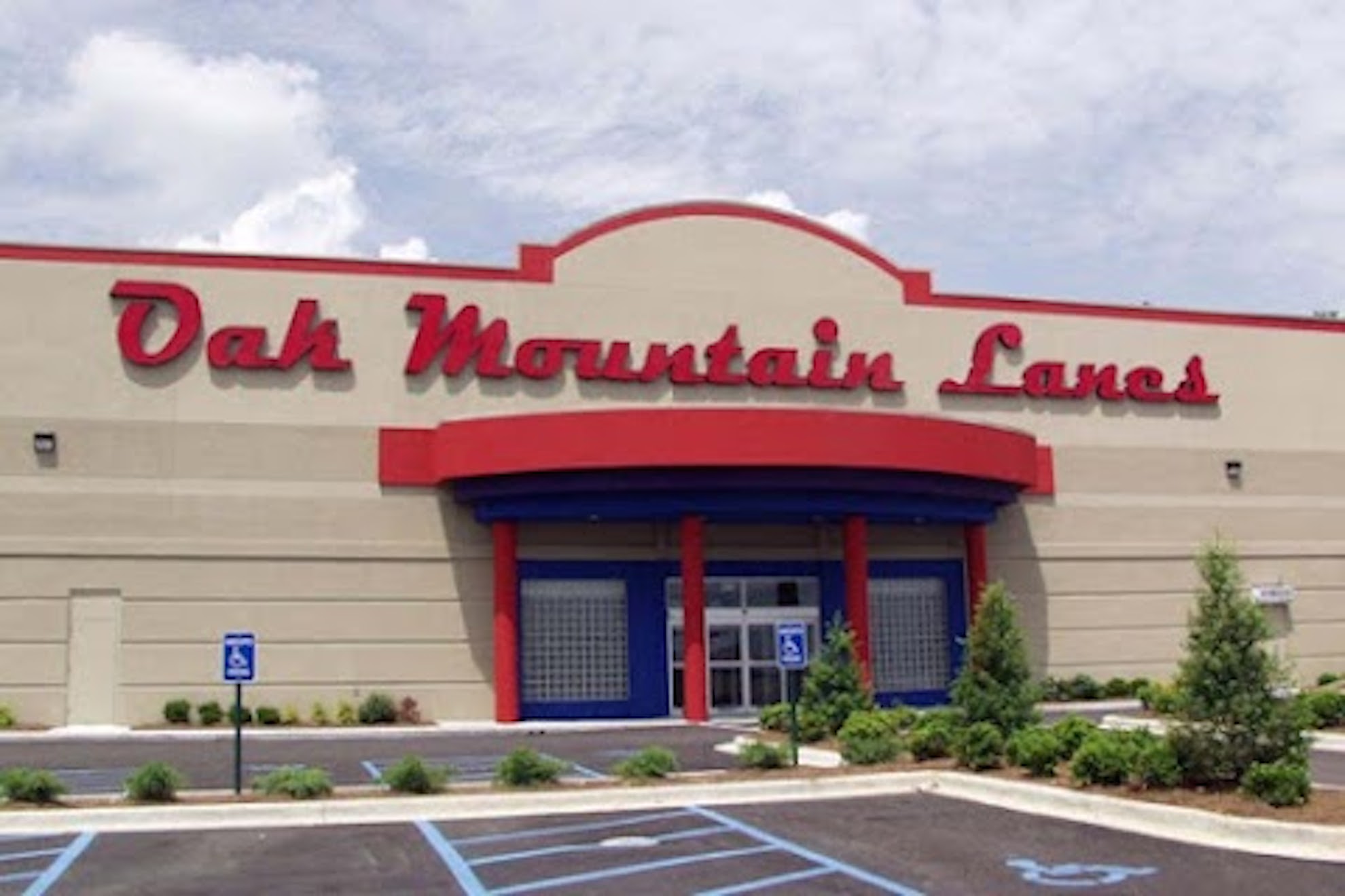 The tan and red exterior of Oak Mountain Lanes with a large red sign above the blue glass entrance.