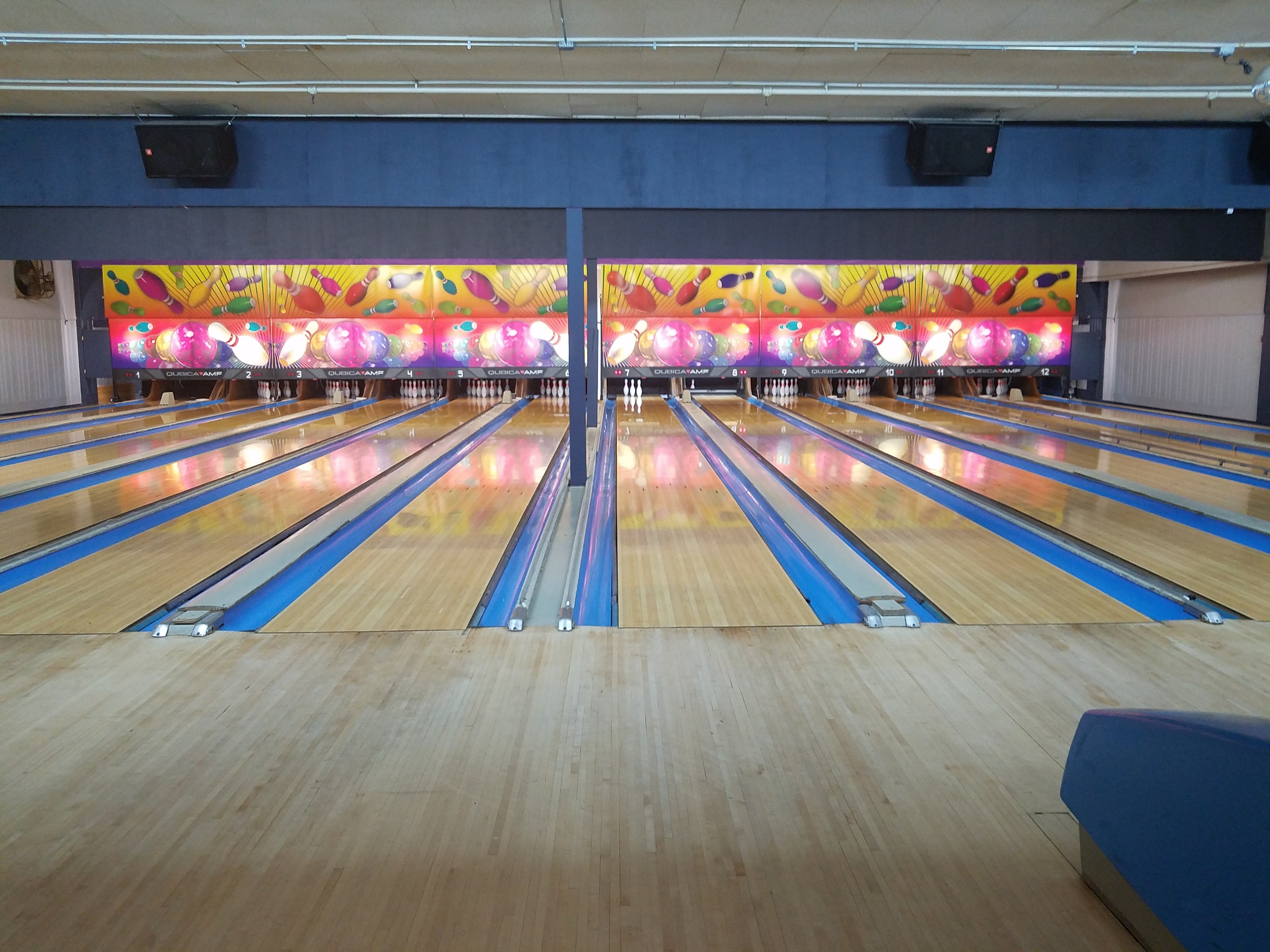 A symmetrical view of multiple polished wood bowling lanes at Larkfield Lanes.