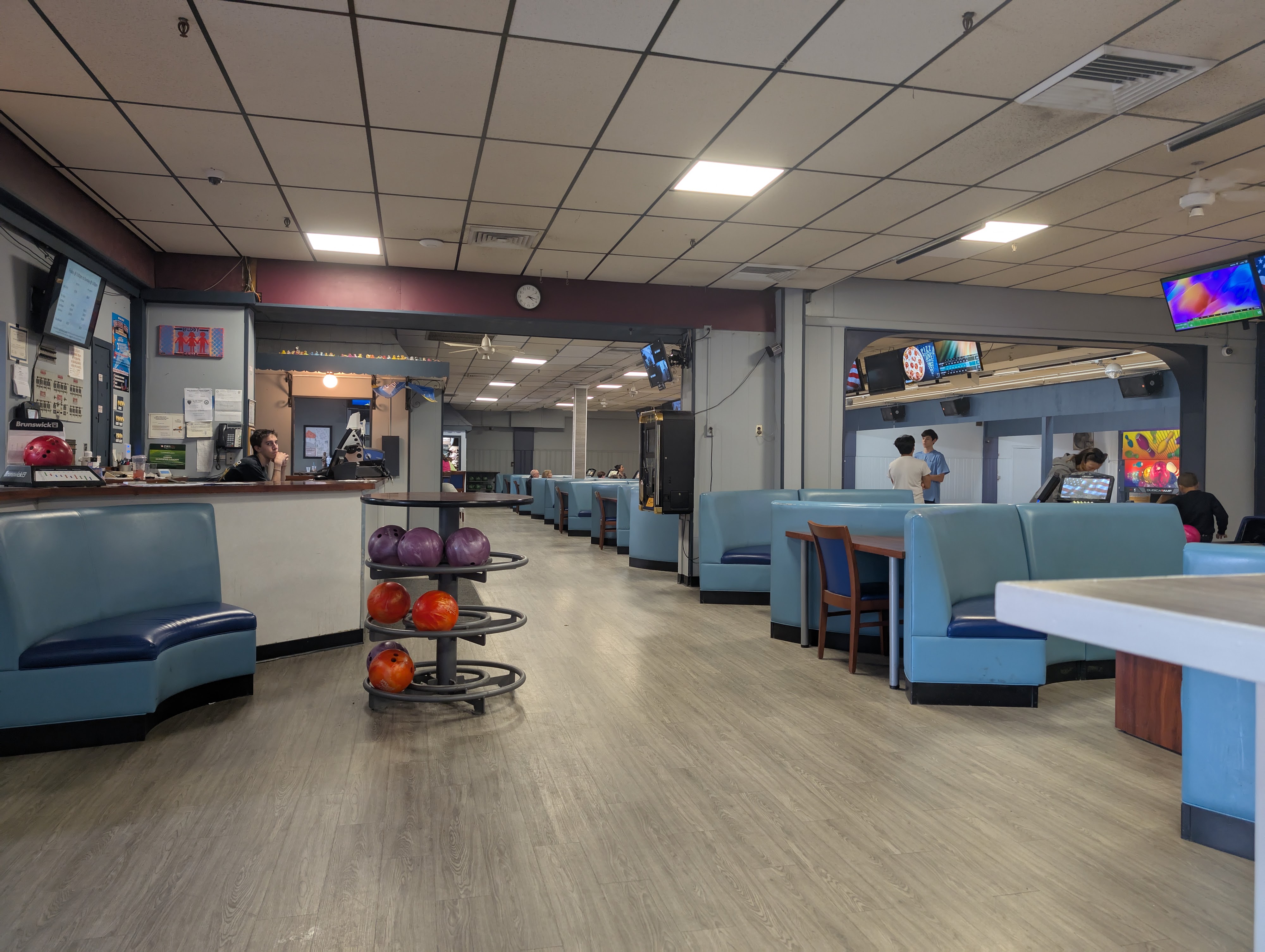 Interior view of a bowling center featuring blue booth seating, a ball rack, and the front desk.