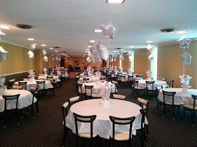 A large event room with many round tables covered in white tablecloths and decorated with silver star balloons.