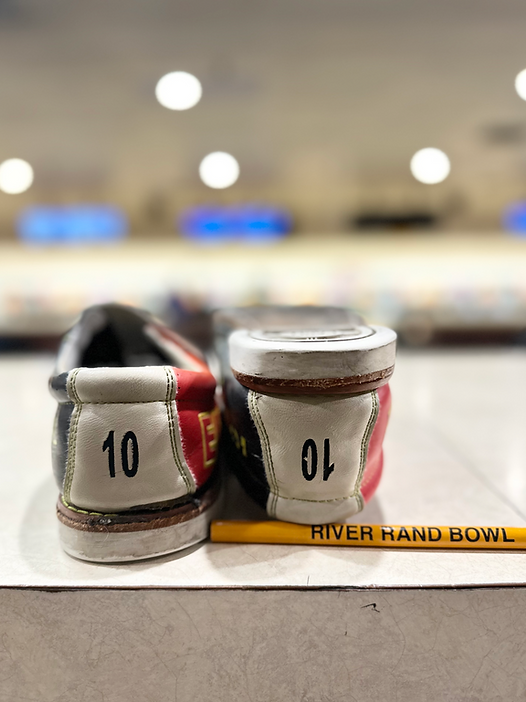 A close-up of two bowling rental shoes, one size 10 and one size 01, with a yellow pen from River Rand Bowl.
