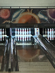 A straight-on view down two bowling lanes, showing set pins on lanes 10 and 11.