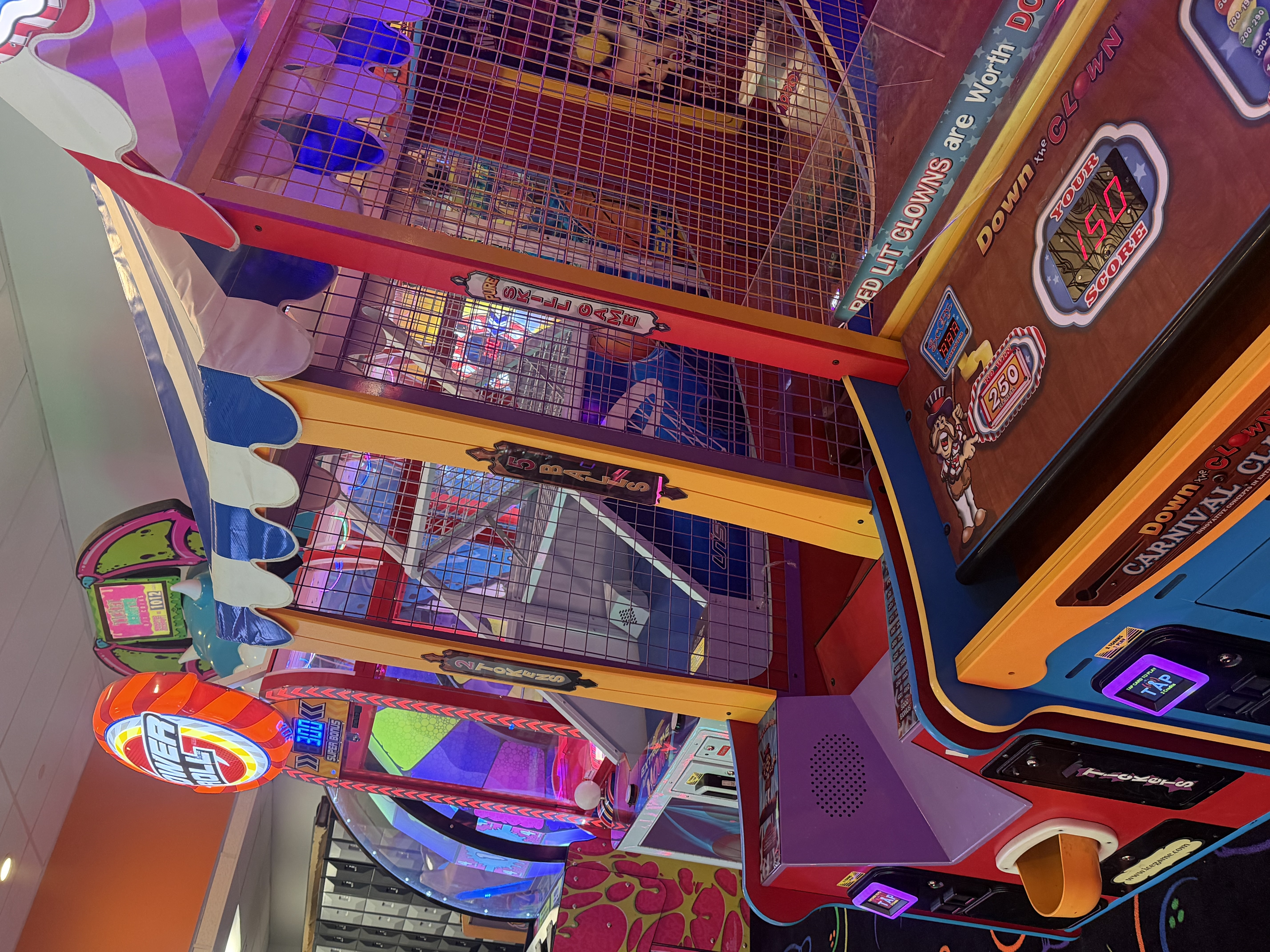 A vertical view of colorful carnival-themed arcade games including Down the Clown and Power Roll.
