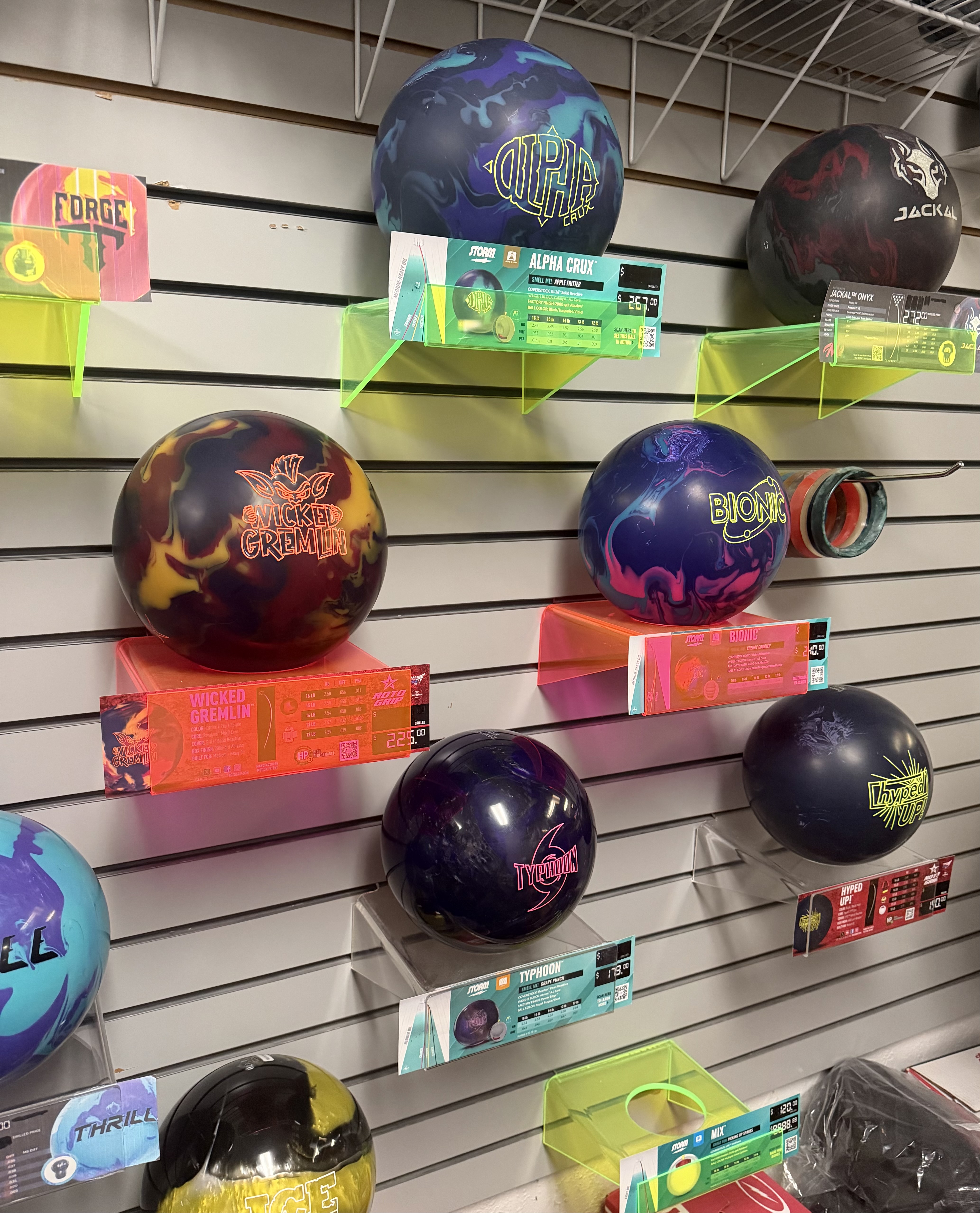 A display of professional bowling balls on neon shelves at a pro shop.
