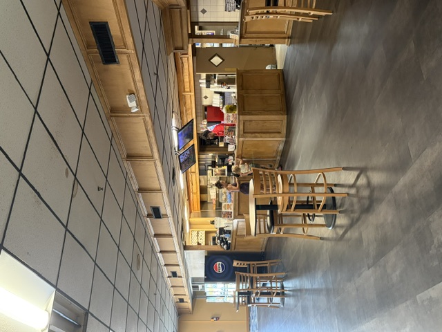 A wood-paneled concessions counter with digital menus and high-top seating in a bowling center.