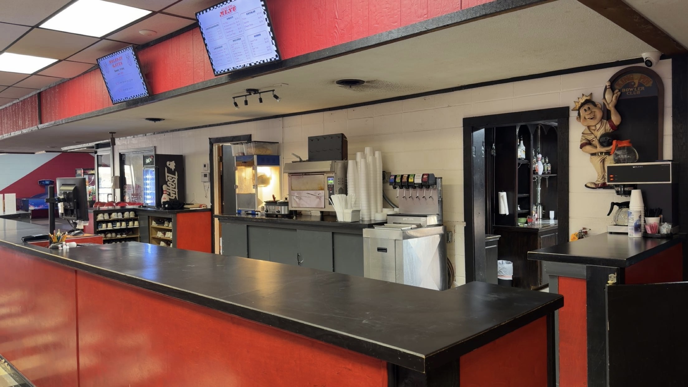 The red and black snack bar counter at College Bowl featuring food service equipment and digital menu boards.